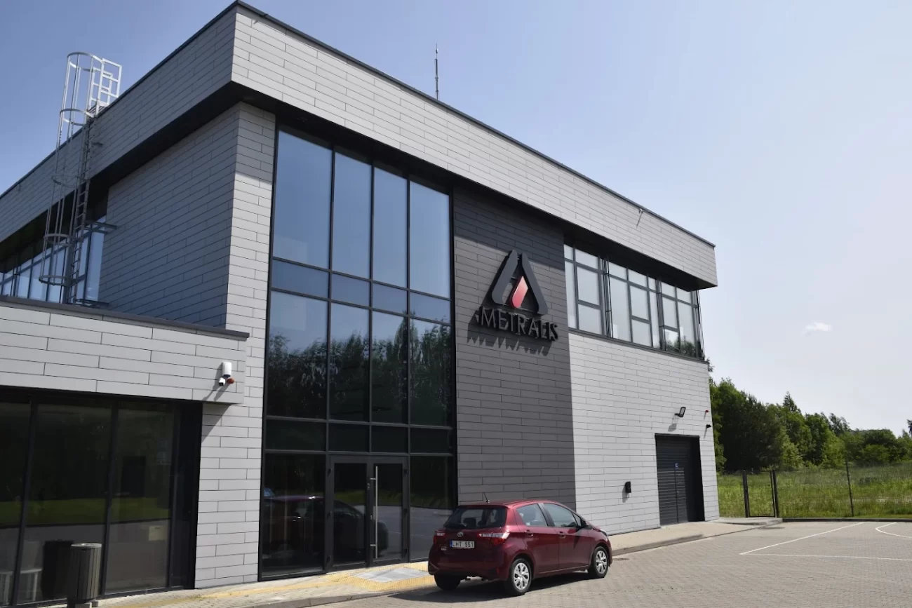 Modern Metralis laboratory building with glass facade, visible company logo and parked red car, precious metal analysis lab