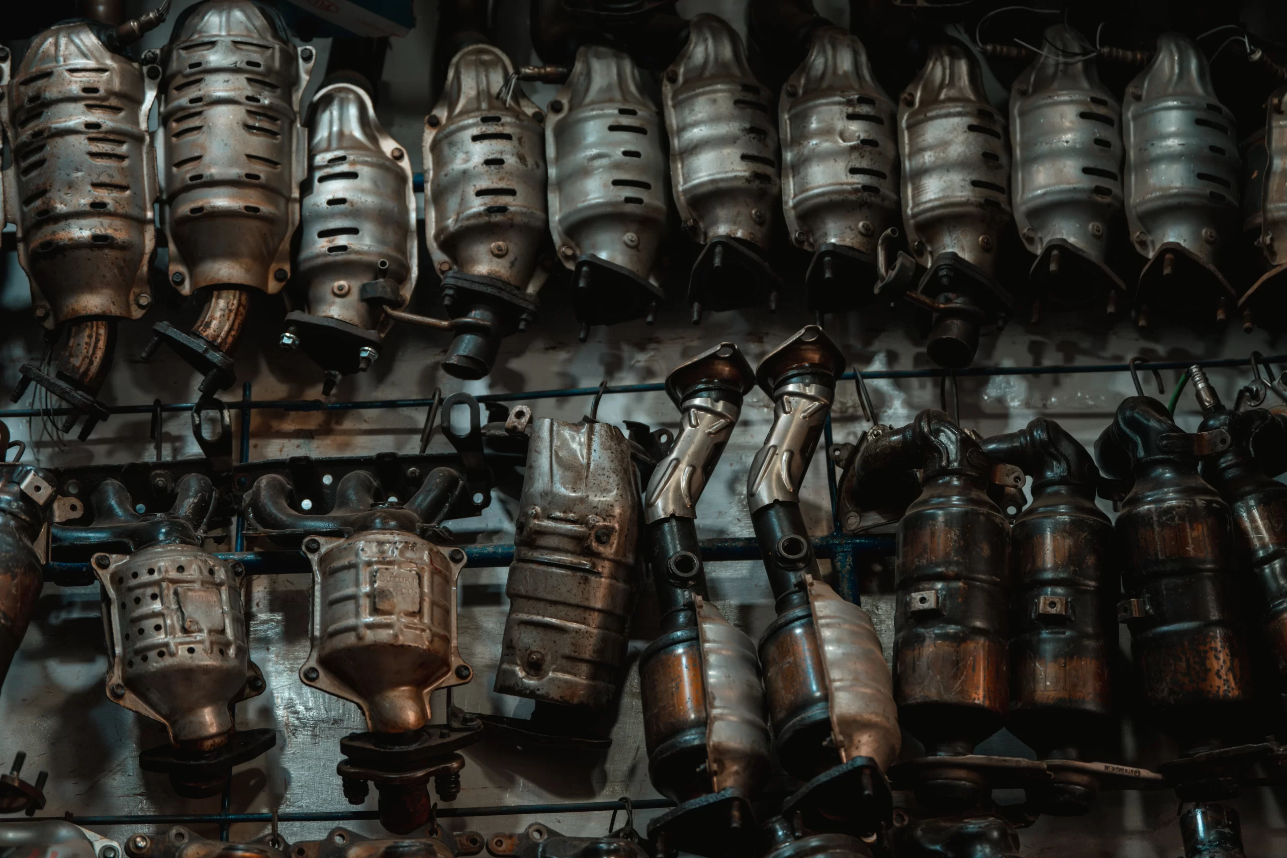 Worn automotive catalytic converters hung on racks for catalyst recycling